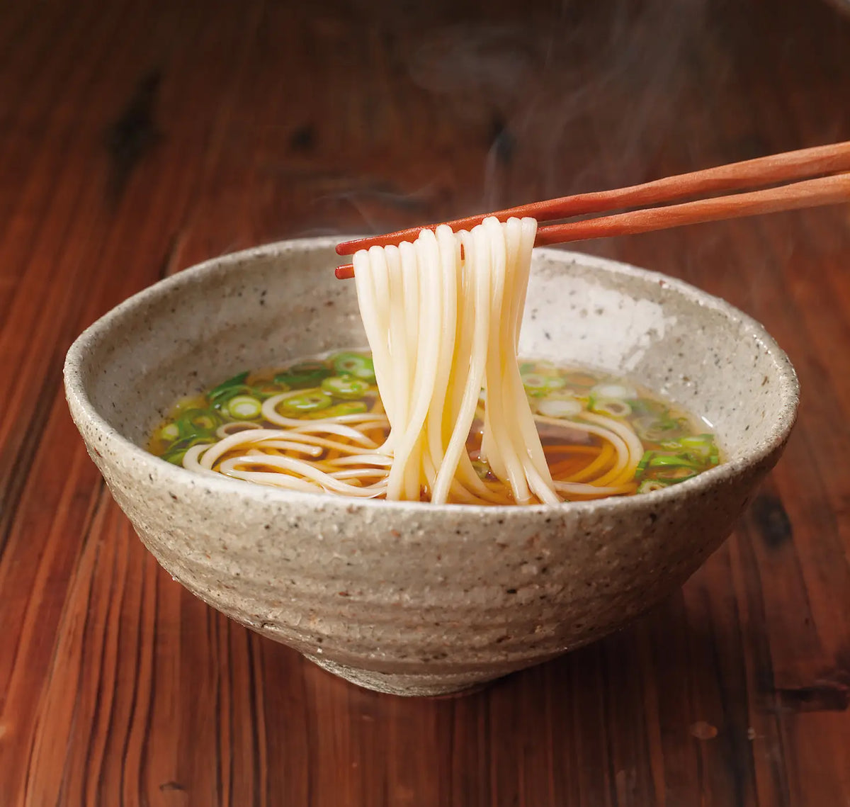 Kayanoya Udon Noodle bowl with chopsticks lifting noodles from a wooden surface