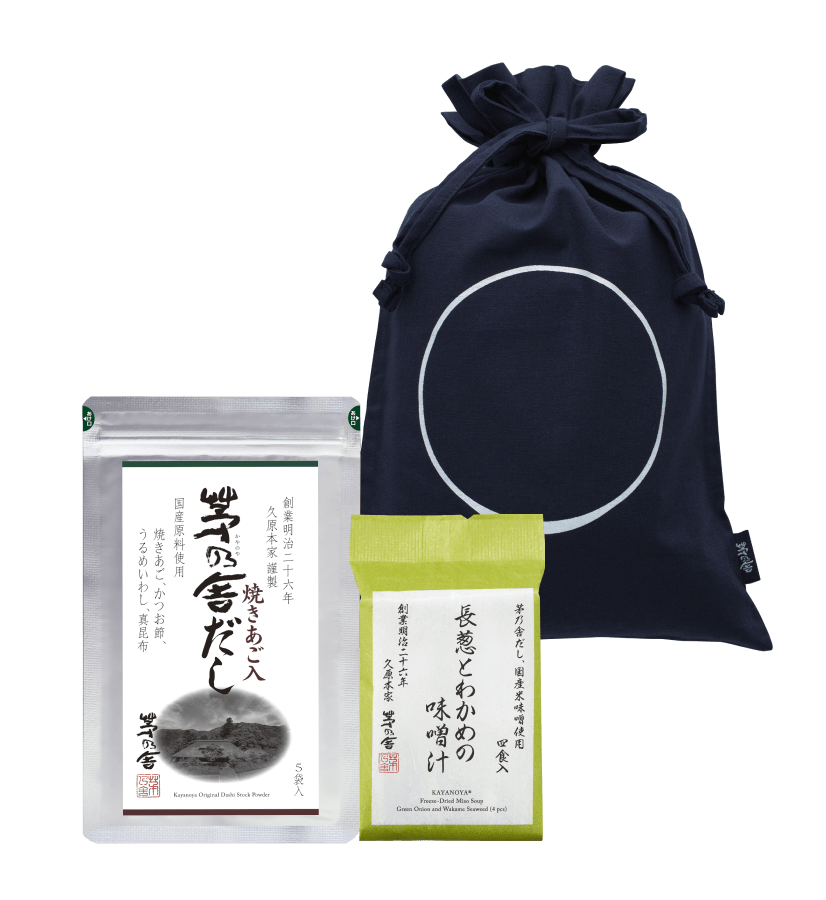 The Custom Umami Gift Bag - Medium by Kayanoya USA - Kubara Honke USA, Inc. includes a navy organic cotton drawstring bag beside two Japanese food packages: Kayanoya Dashi Stock in silver and a smaller yellow-green package.