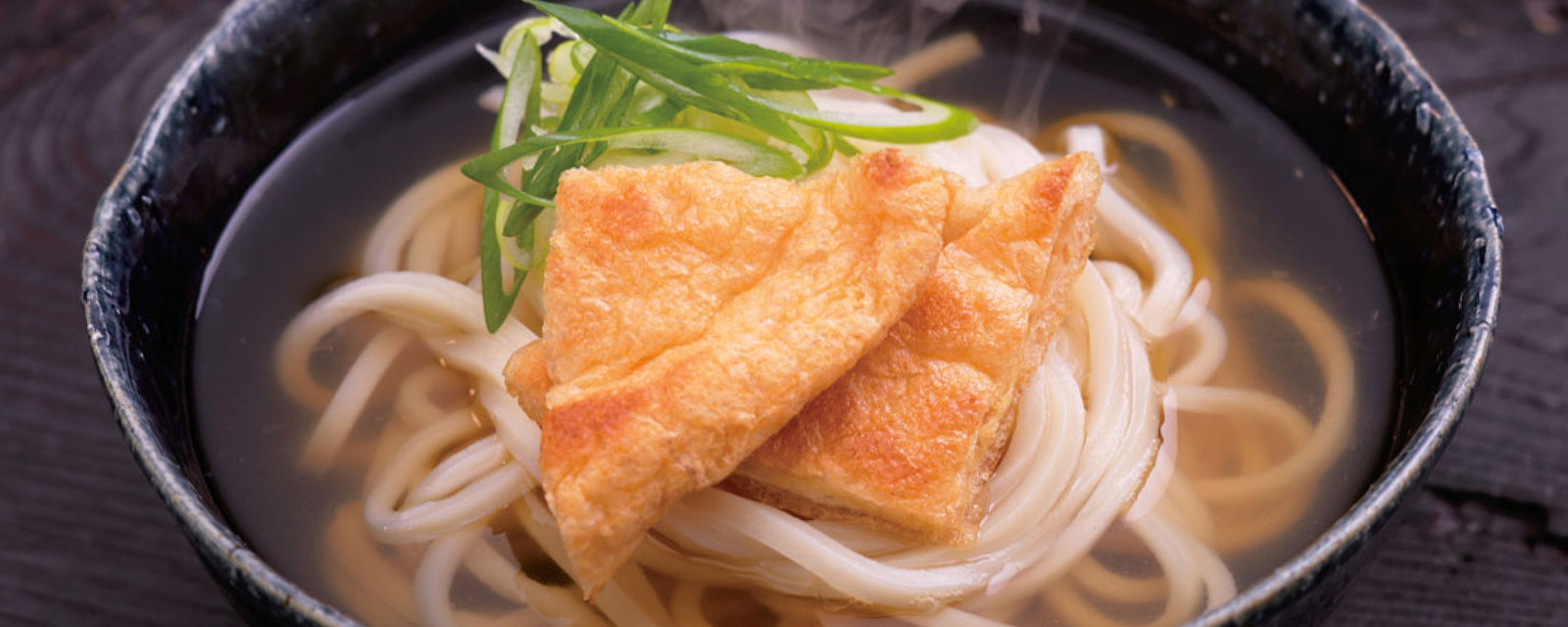 Udon noodle soup topped with fried tofu and green onions