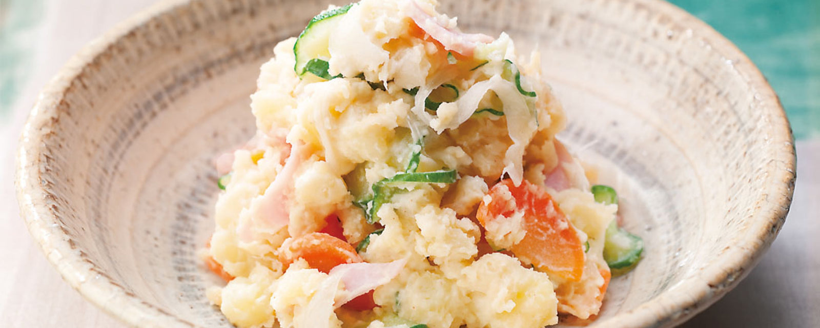 Japanese potato salad with cucumber, carrot, and ham in a ceramic bowl