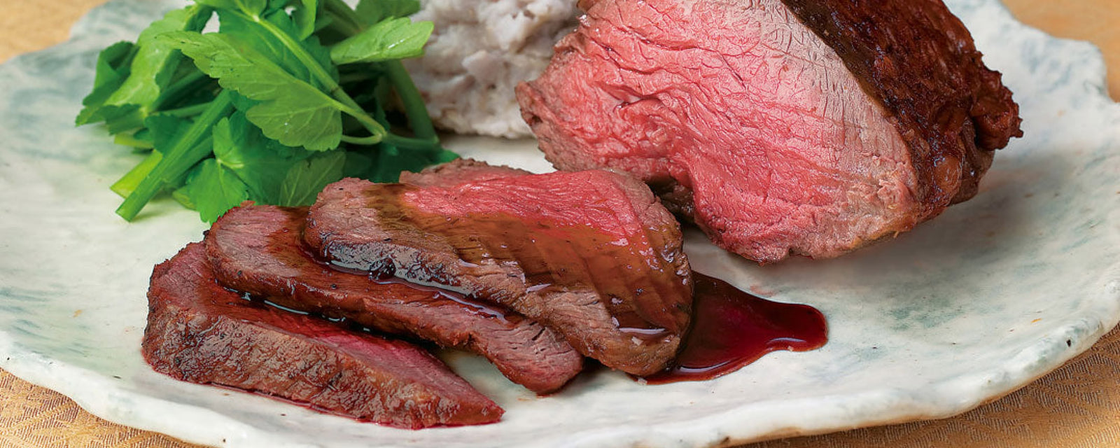 Sliced roast beef with gravy served with greens and mashed potatoes