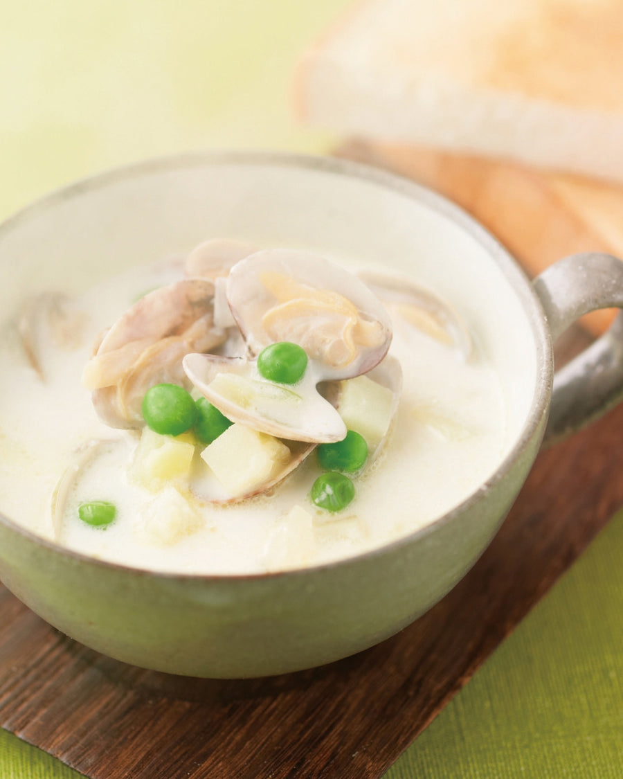 Creamy clam chowder with peas and potatoes in a cup, served with toasted bread.