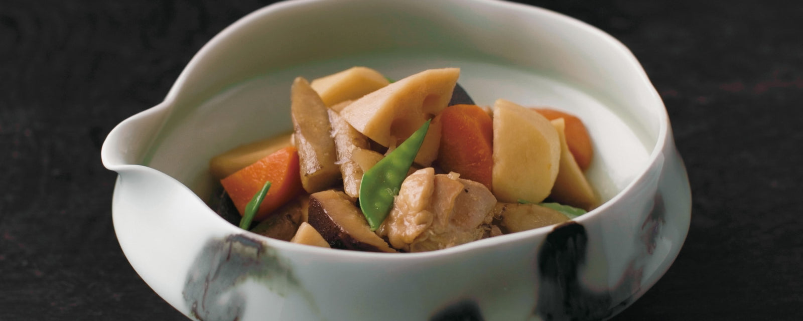 Simmered Japanese vegetables featuring lotus root, carrot, burdock root, shiitake mushroom, and chicken, gently braised in a light soy-based dashi broth and garnished with snow peas.
