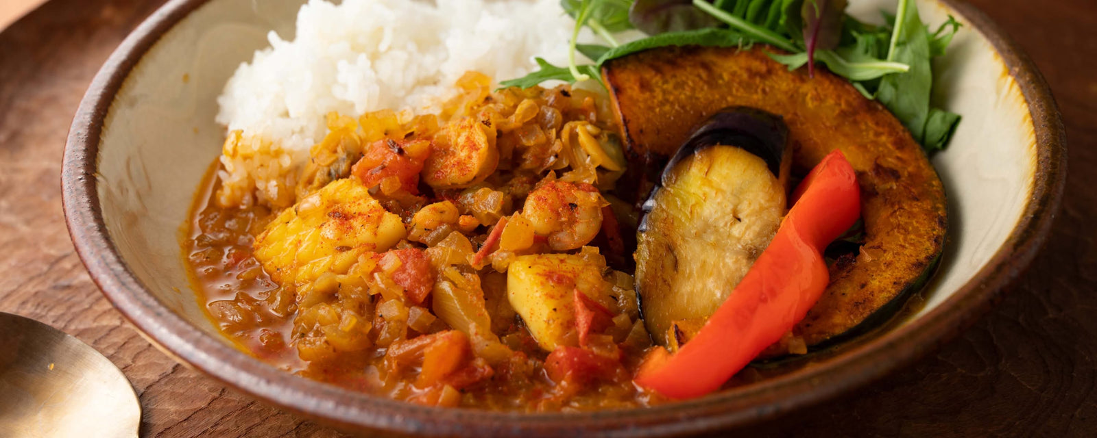 Seafood curry with seafood mix and vegetables, served alongside white rice and roasted pumpkin, eggplant, and red pepper.