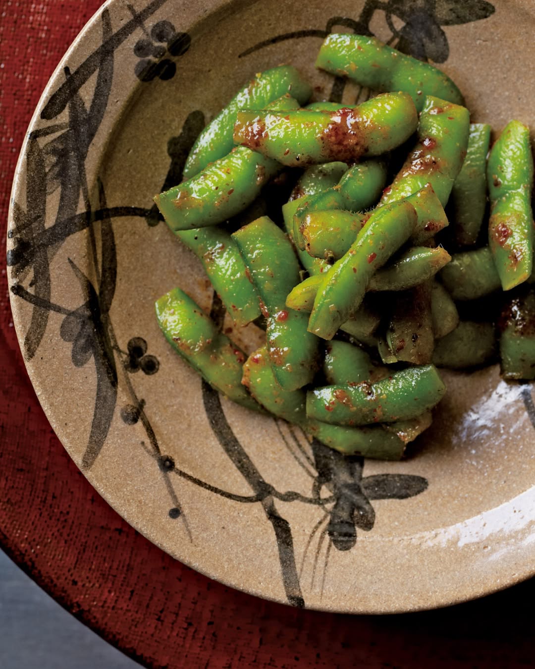 Spicy edamame pods tossed with chili seasoning, served in a rustic ceramic bowl.