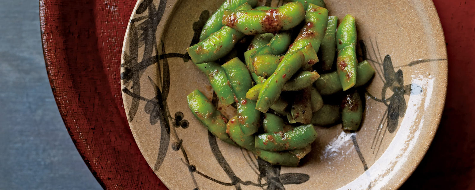 Spicy edamame pods tossed with chili seasoning, served in a rustic ceramic bowl.