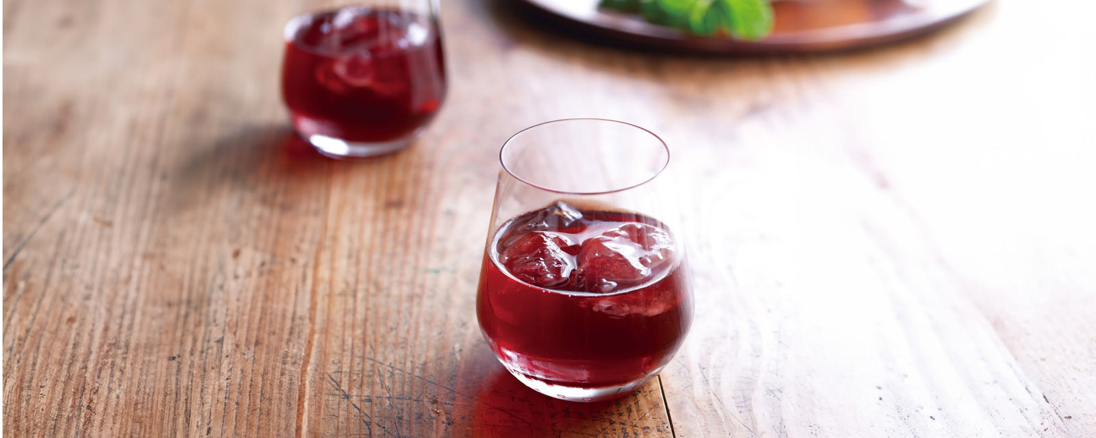 A glass of Kyoho red wine spritz with ice on a wooden table.