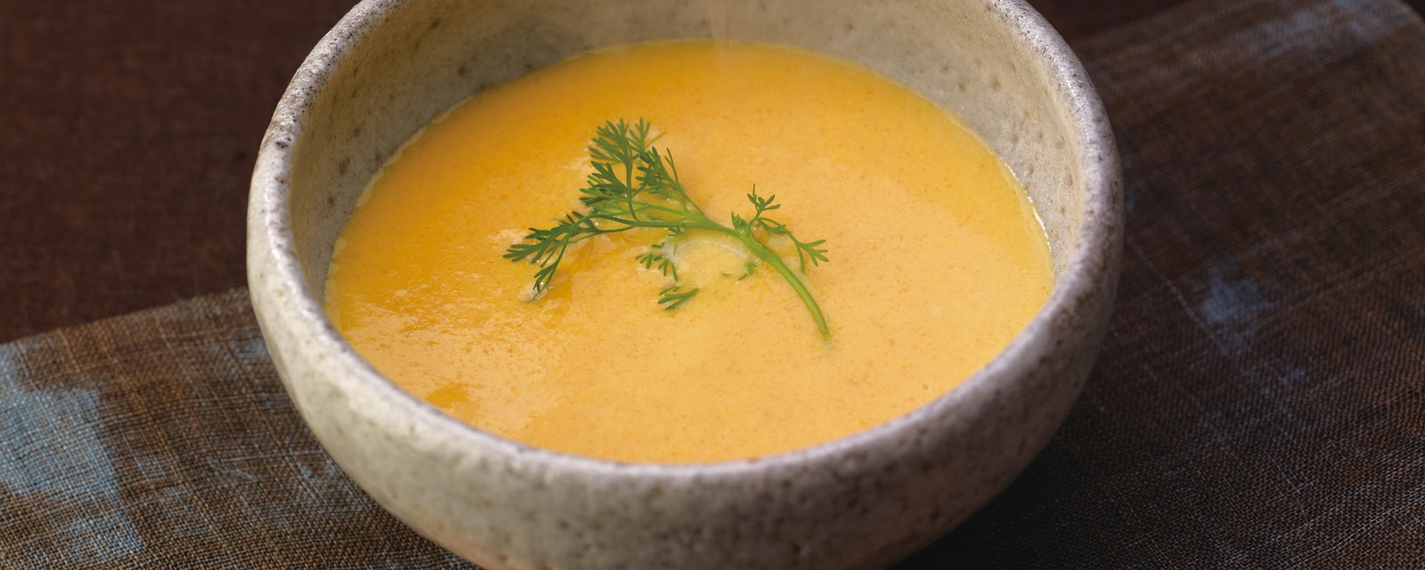 Umami rich carrot soup in a textured ceramic bowl
