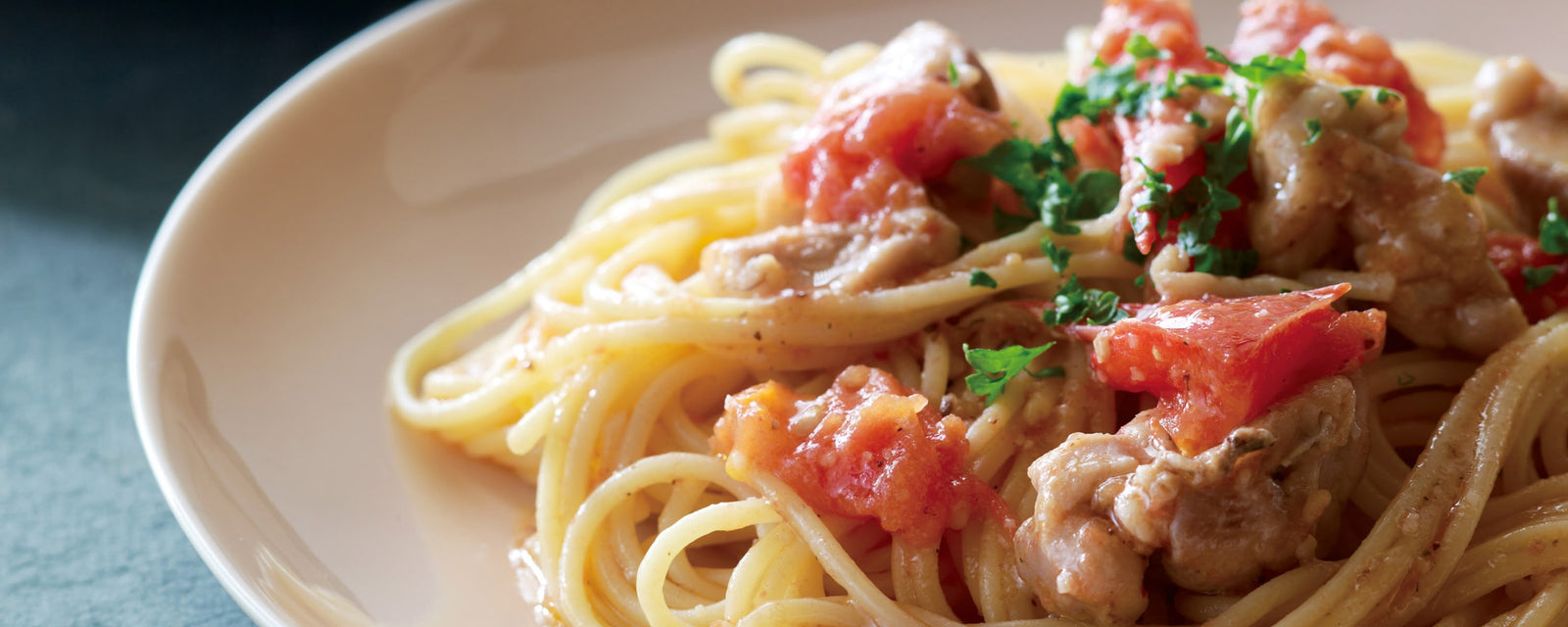 Spaghetti with chicken and fresh tomato topped with parseley