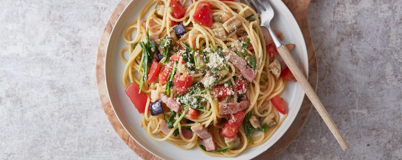 Spaghetti with bacon, vegetables, and grated cheese
