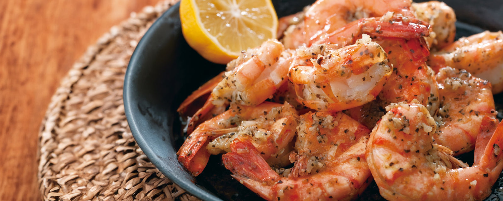 A bowl of garlic shrimp served with a lemon wedge on the side.