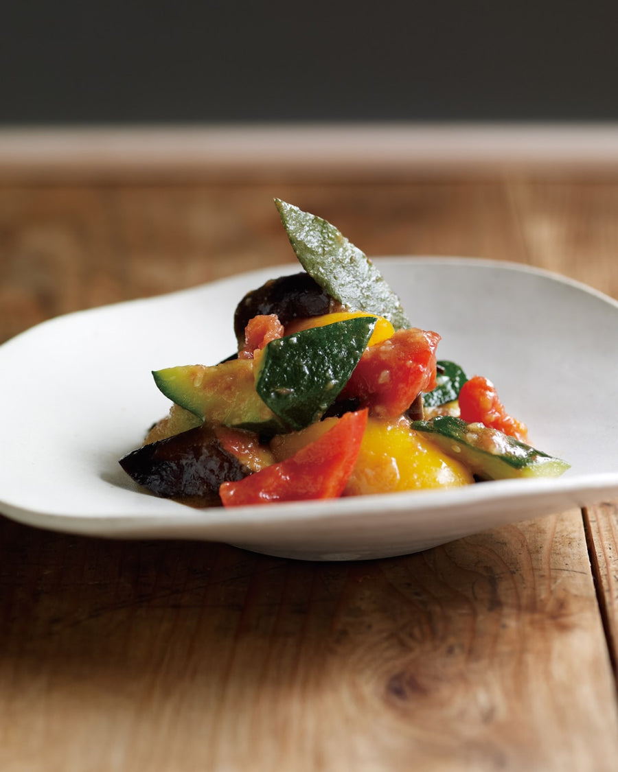 A small plate of chunky summer vegetable ratatouille with zucchini, eggplant, and tomatoes.