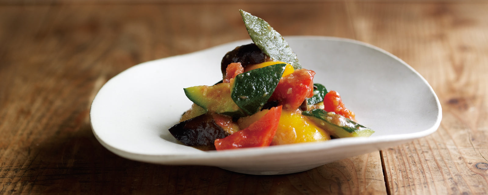 A small plate of chunky summer vegetable ratatouille with zucchini, eggplant, and tomatoes.