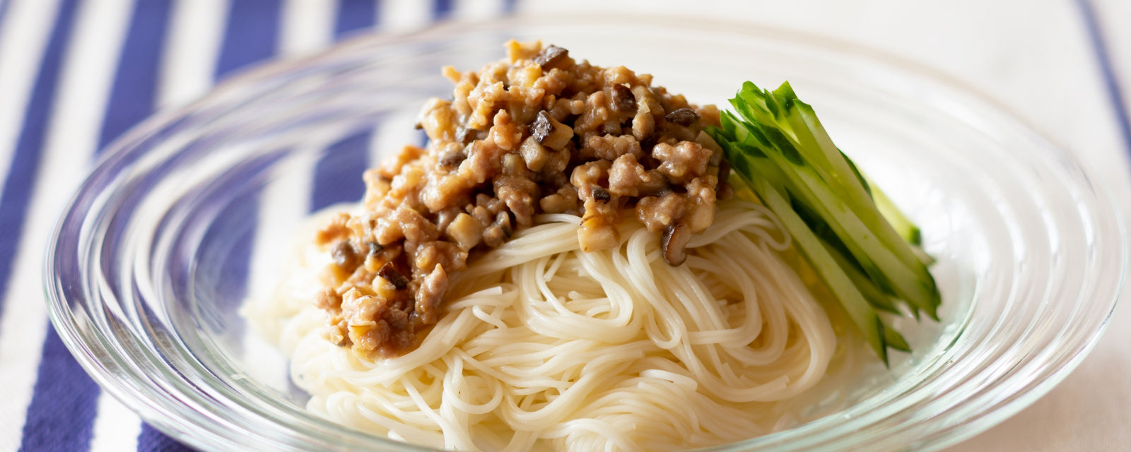 A bowl of zhajiang-style somen noodles topped with minced meat sauce and sliced cucumber.