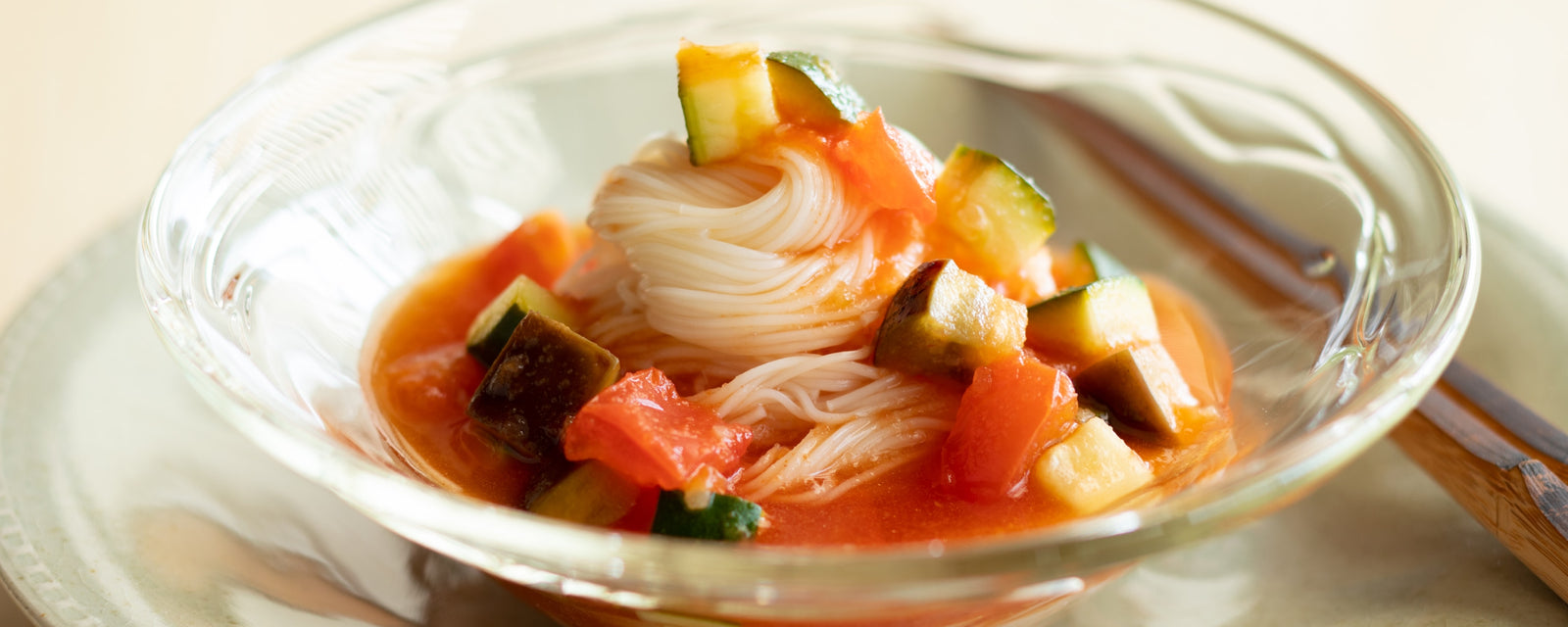 A bowl of tomato somen noodles served with diced vegetables in a light tomato broth.