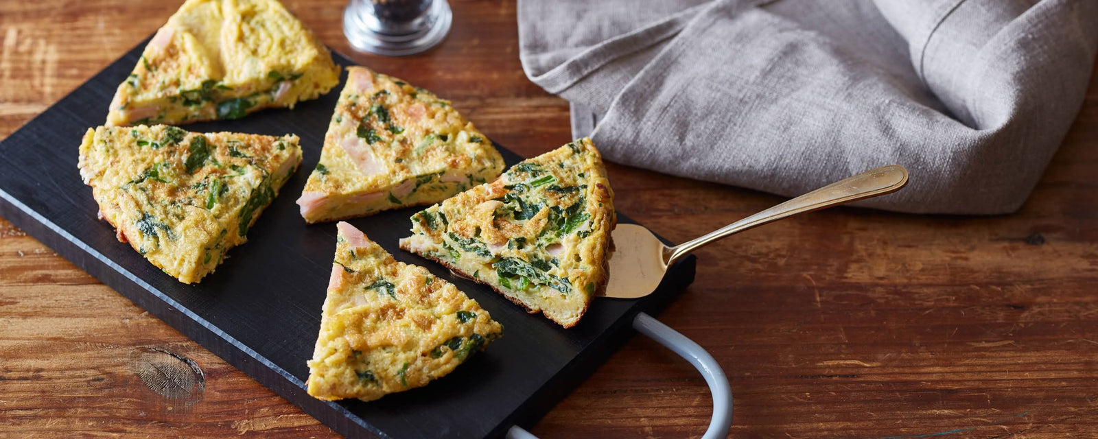 Sliced omelette with spinach and ham served on a board