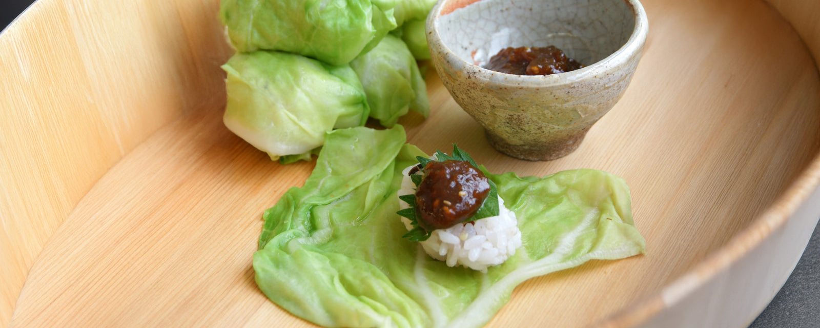 A spring cabbage leaf wrapped around a small rice ball topped with miso sauce.
