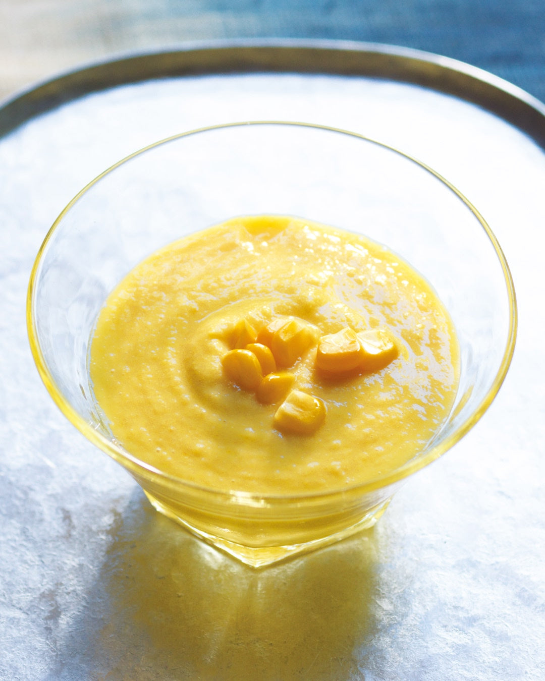 A bowl of creamy corn soup topped with sweet corn kernels.