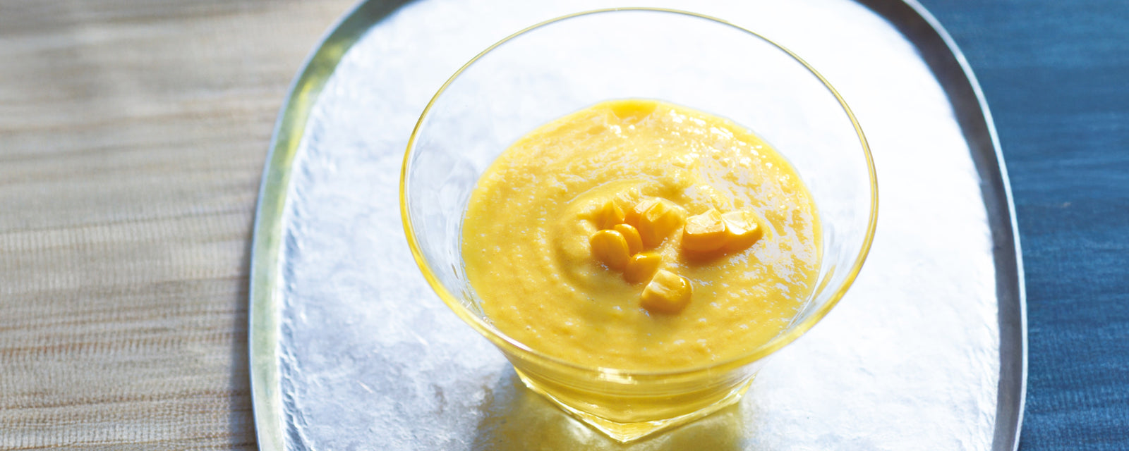 A bowl of creamy corn soup topped with sweet corn kernels.