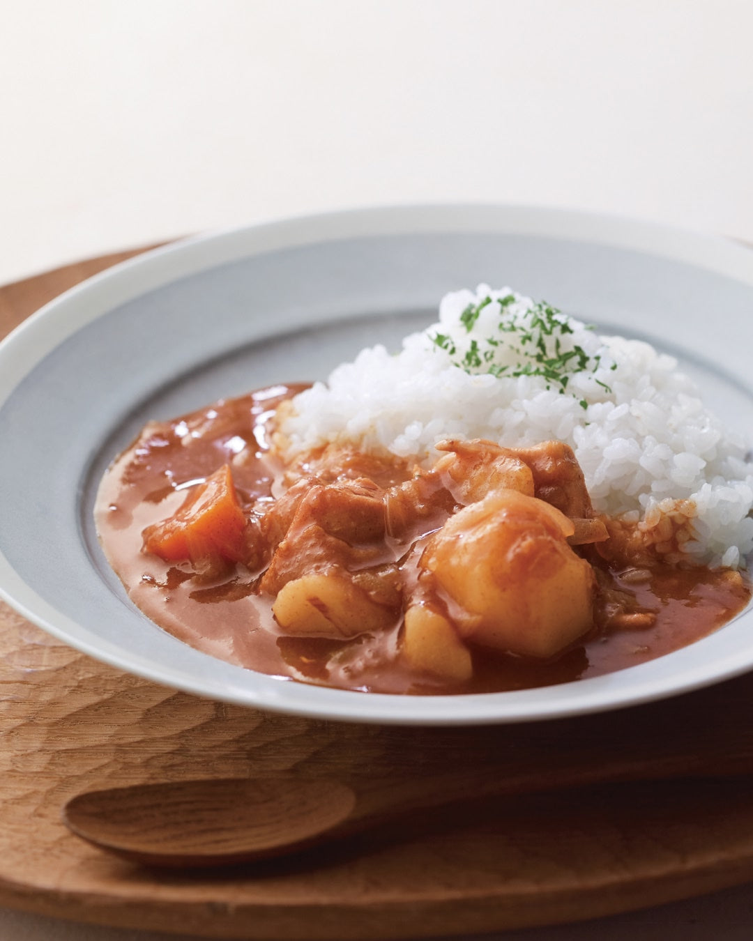 A plate of Japanese curry with chicken and potatoes served alongside steamed rice.