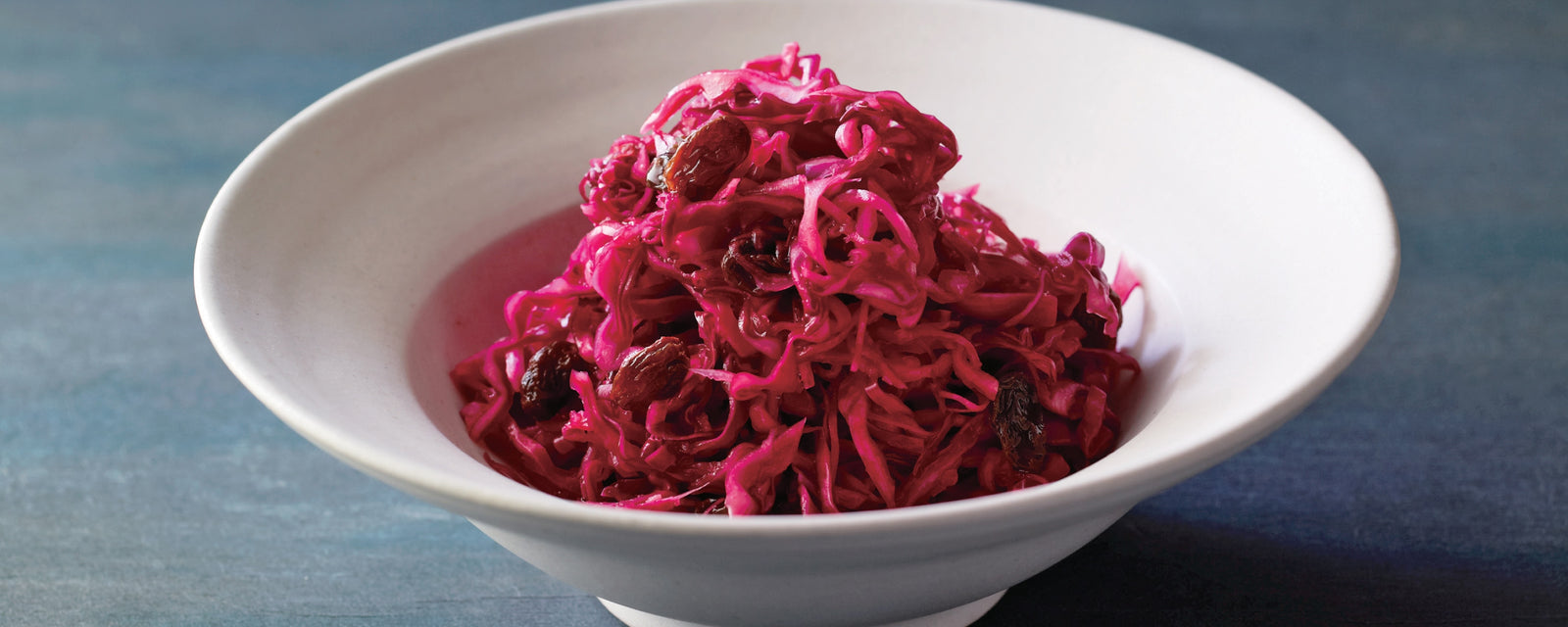 Red cabbage sauerkraut with raisins served in a white bowl.