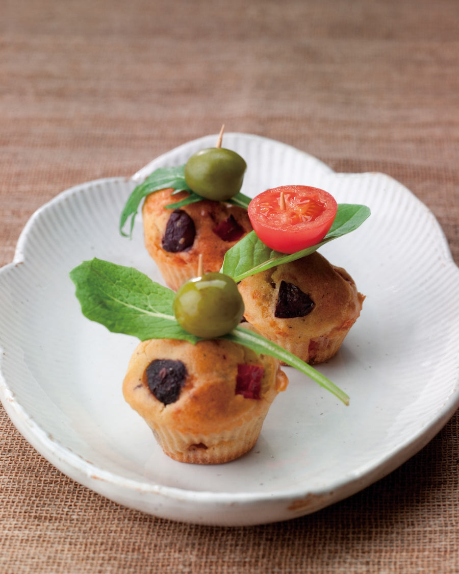 Savory petits fours with olives and red peppers served on a white plate.