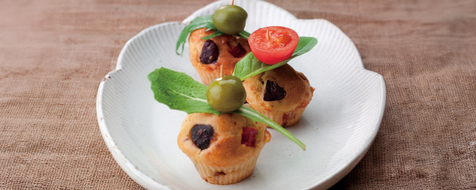 Savory petits fours with olives and red peppers served on a white plate.