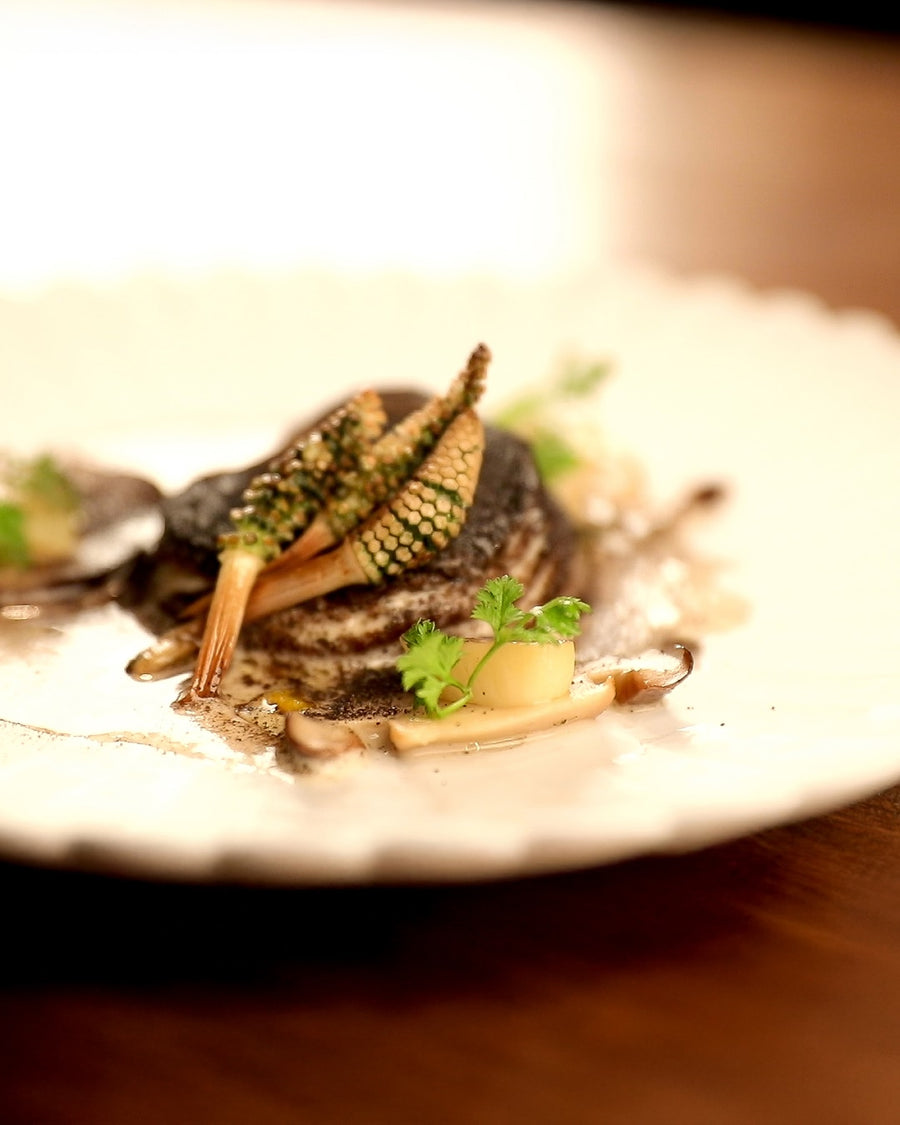 Shiitake mushroom confit served with herbs on a white plate.
