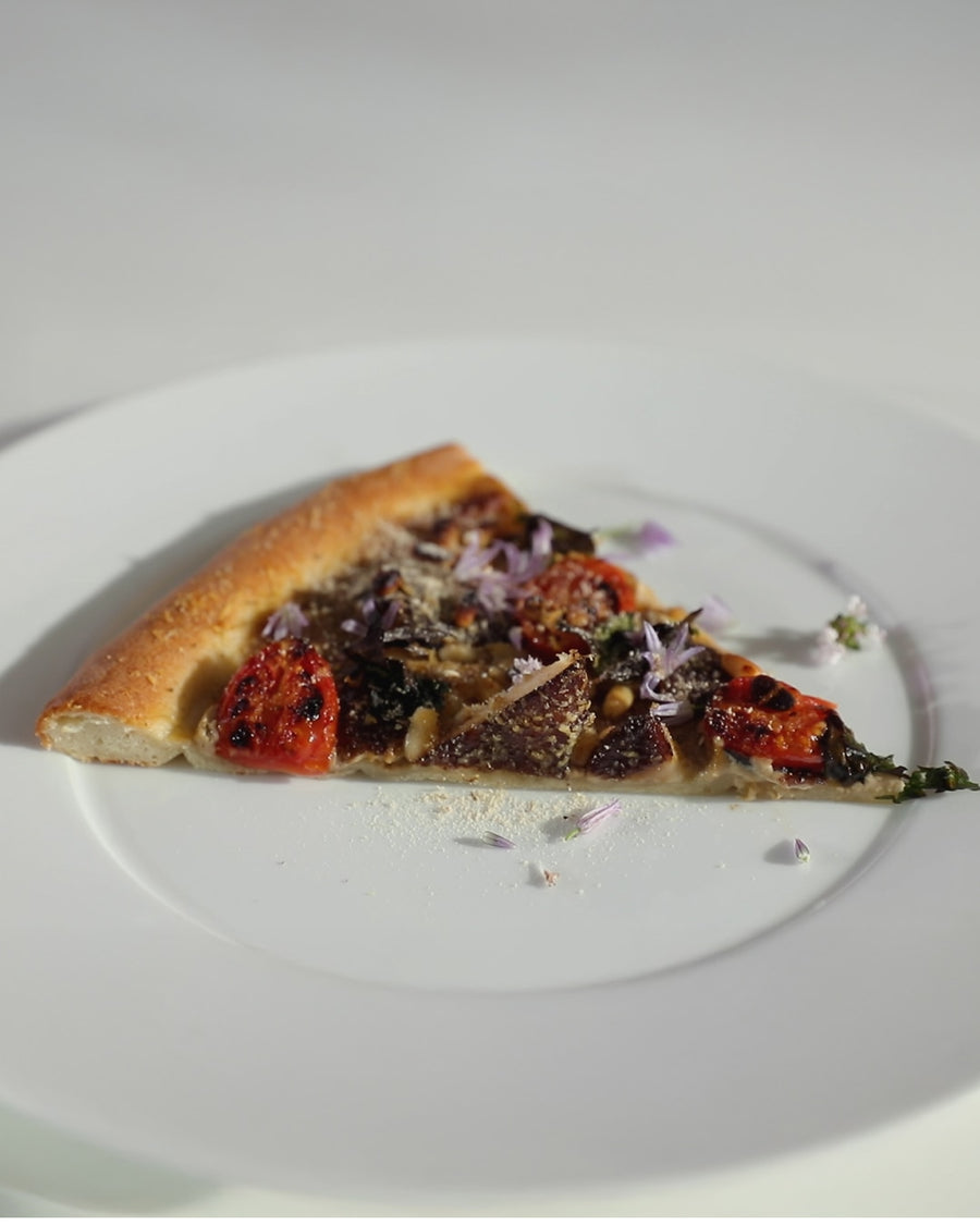 Slice of shiitake mushroom pizza with roasted tomatoes and herbs on a white plate.