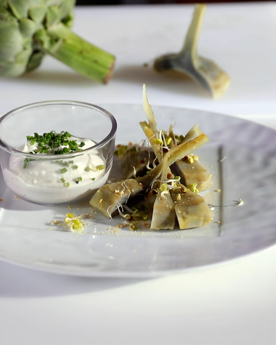 Artichoke salad with tender artichoke pieces served with a creamy dipping sauce on a plate.