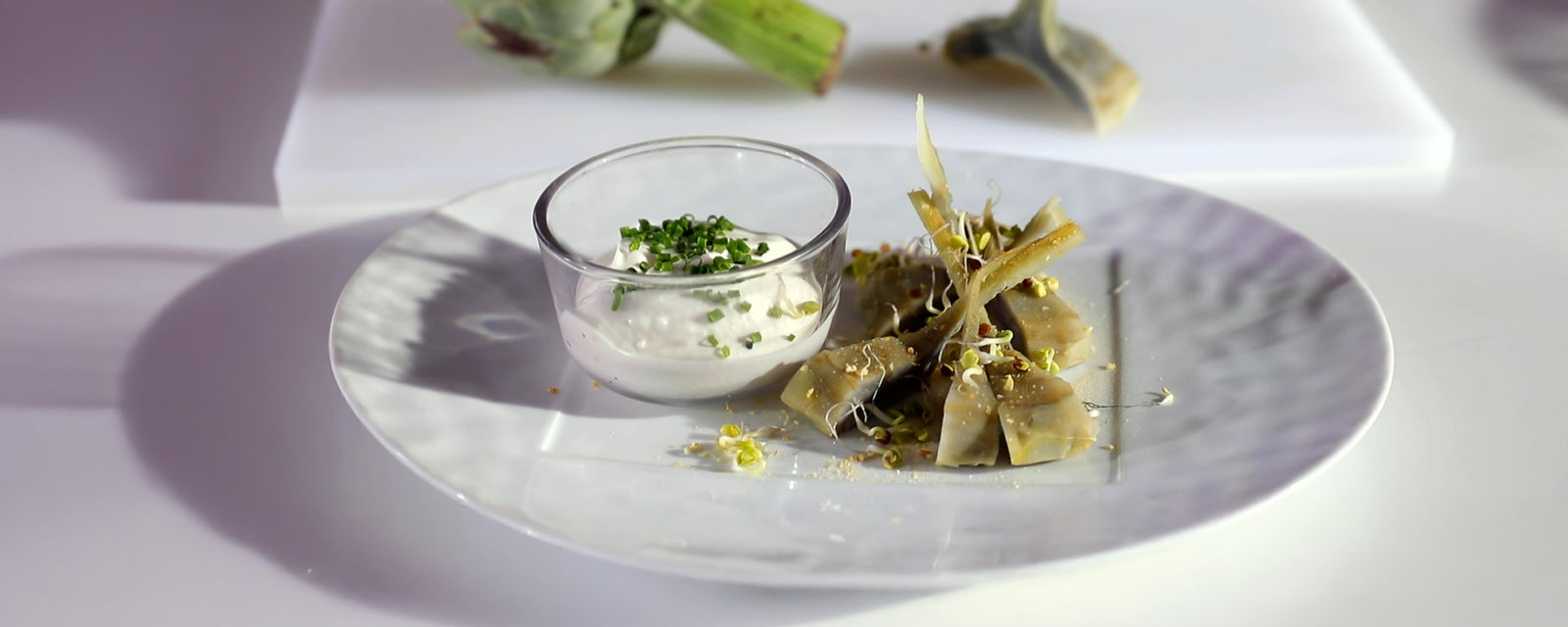 Artichoke salad with tender artichoke pieces served with a creamy dipping sauce on a plate.