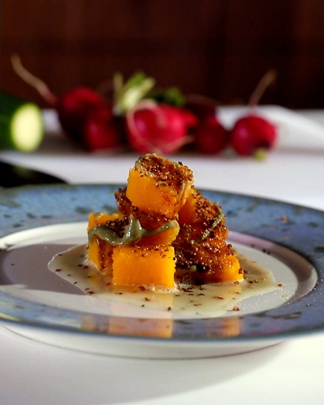 Roasted butternut squash cubes served with a light sauce and seasoning on a plate.