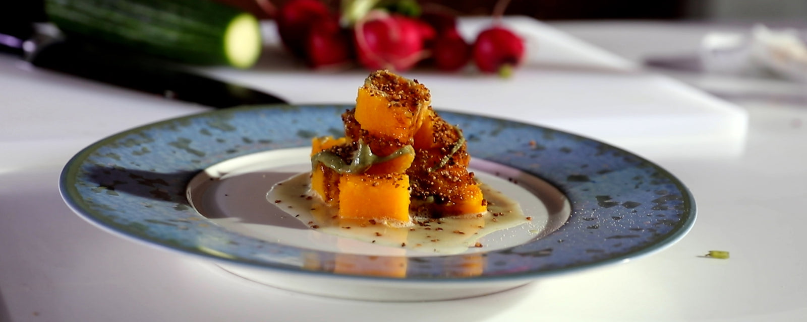 Roasted butternut squash cubes served with a light sauce and seasoning on a plate.