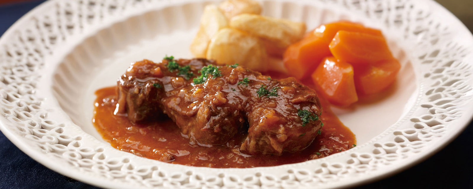 Tender beef shank stew served with potatoes and carrots on a white plate.