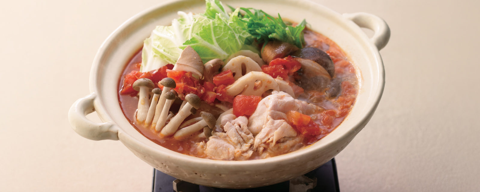 Mushroom-rich tomato miso hot pot with pork and vegetables simmering in a ceramic pot.