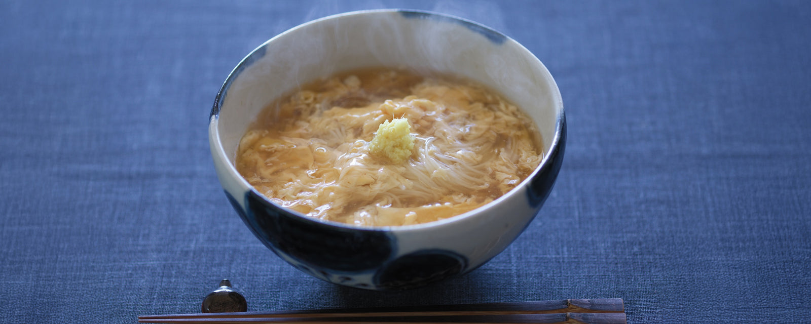Steaming somen noodles in egg drop soup, topped with grated ginger.