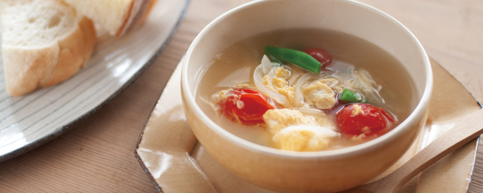 Light tomato and egg soup with cherry tomatoes and green beans served in a bowl.