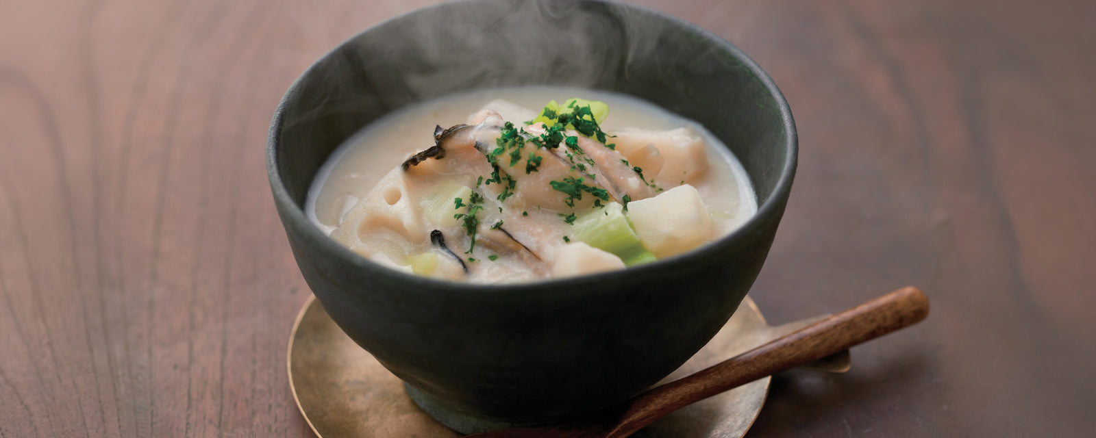 Steaming winter chowder with oysters and root vegetables served in a ceramic bowl.