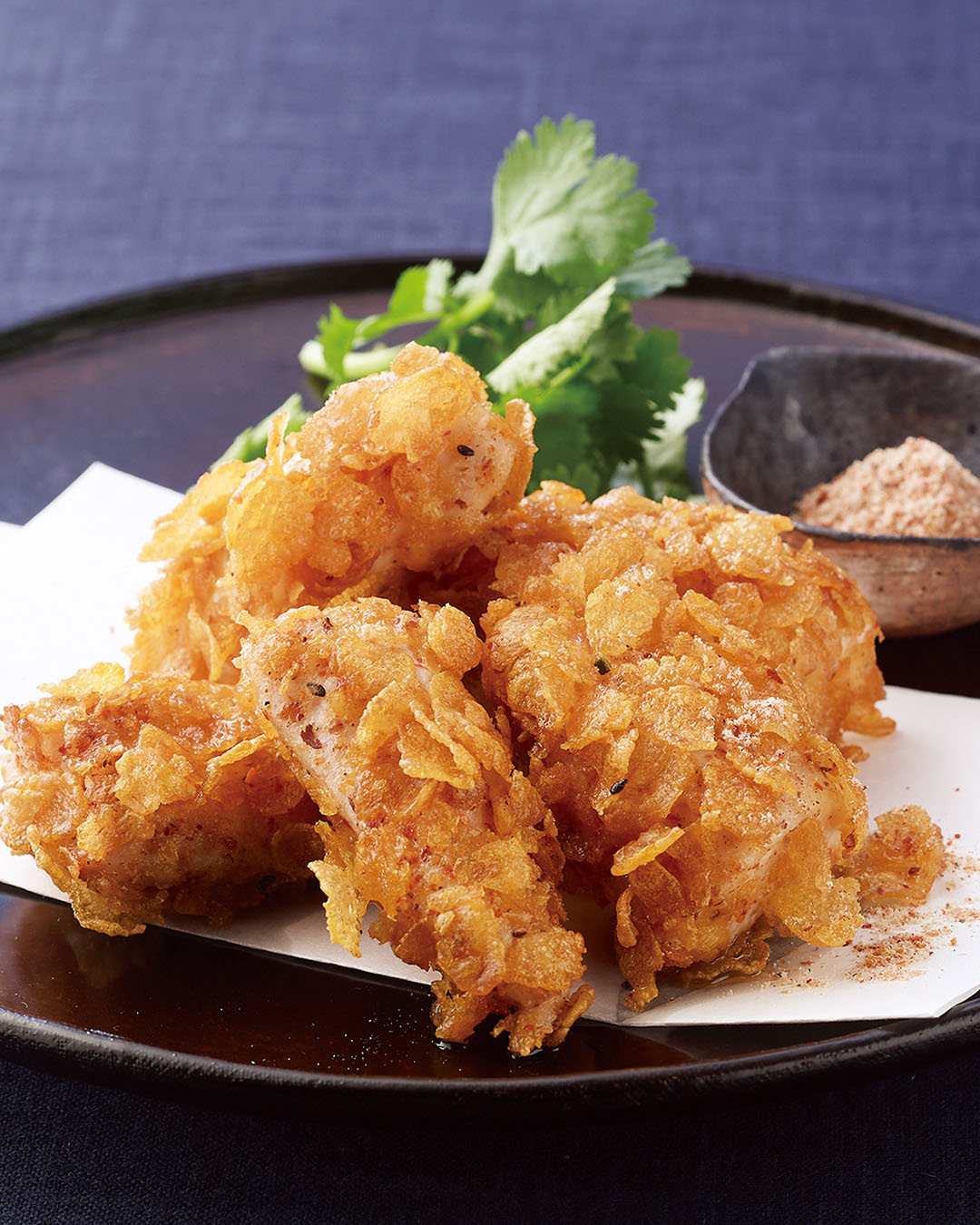 Crispy dashi-infused shichimi sticks served on a plate with herbs and seasoning salt.