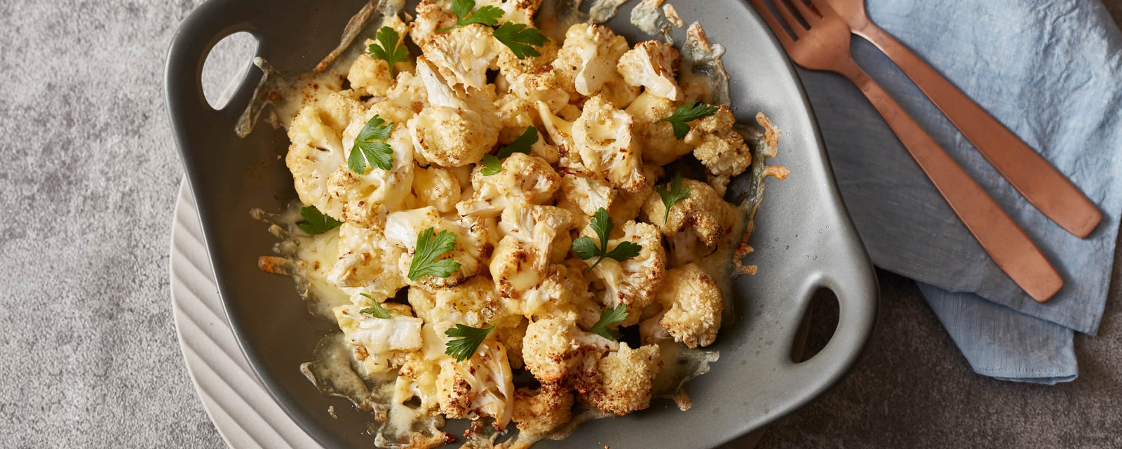 Grilled cauliflower with melted cheese and parsley on a plate