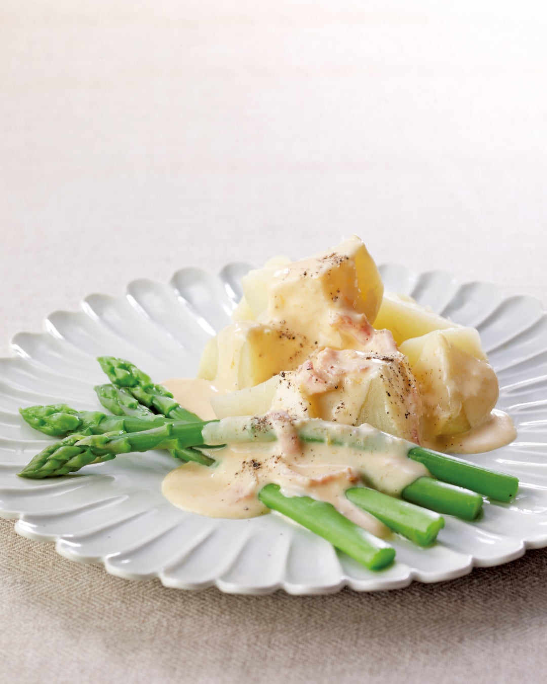 Boiled potatoes and asparagus with creamy sauce on a white plate