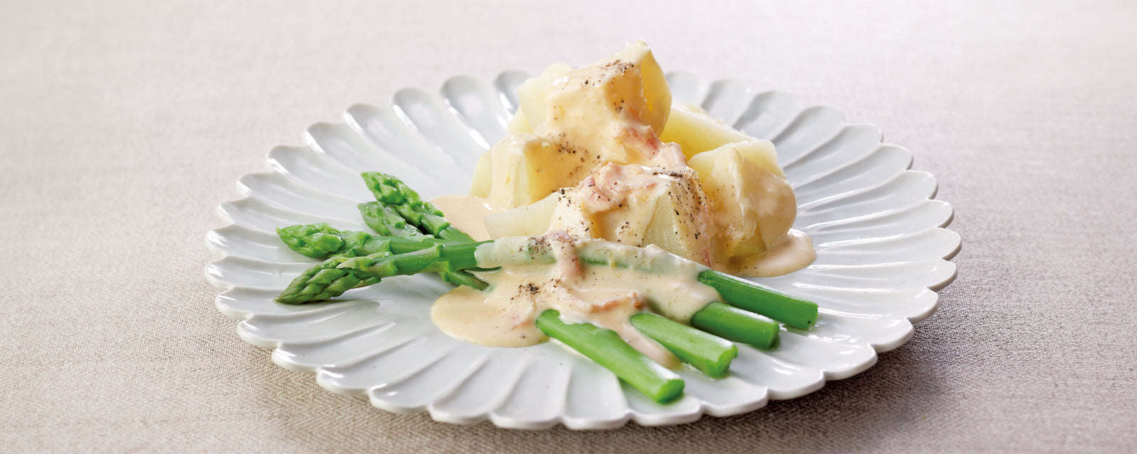 Boiled potatoes and asparagus with creamy sauce on a white plate