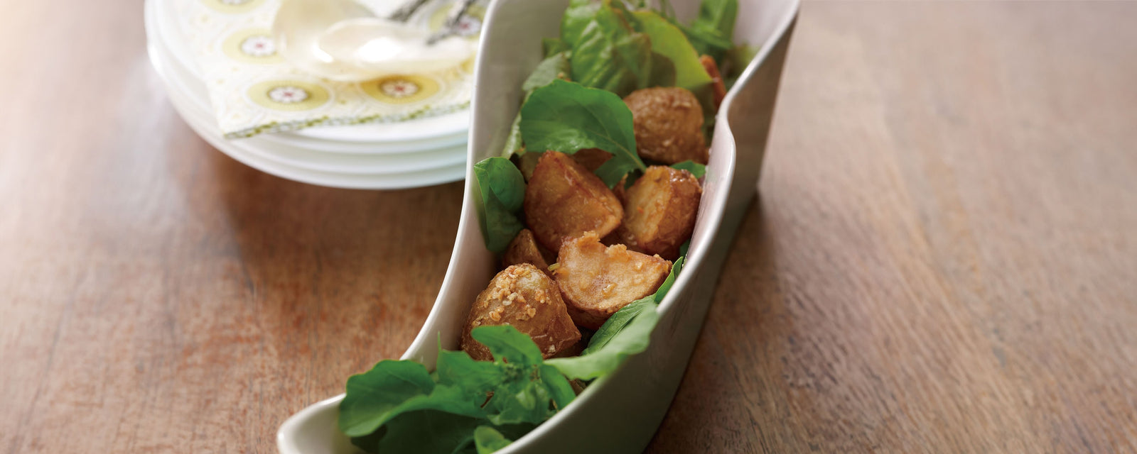 Fried potato bites with leafy greens served in a white dish