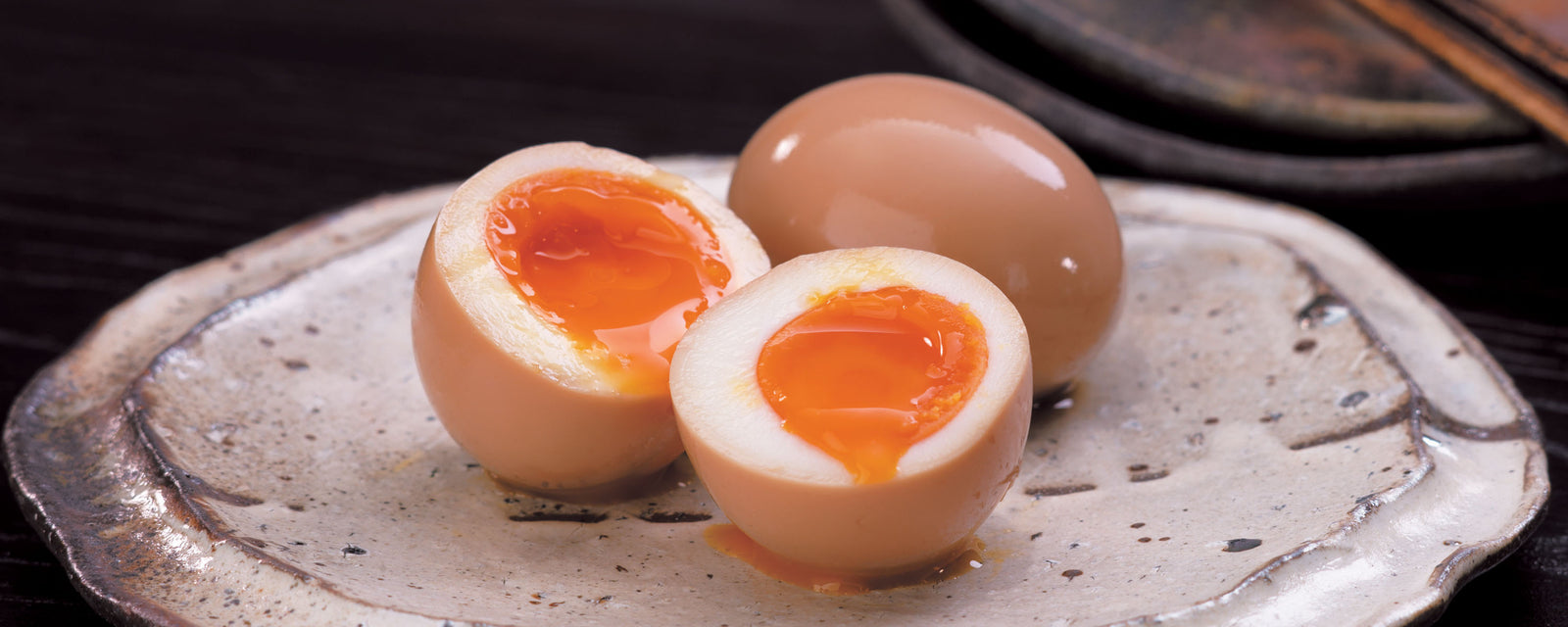 Soft-boiled marinated eggs with runny yolks on a ceramic plate