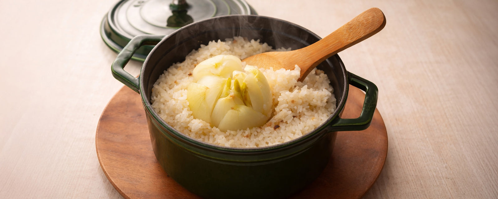 Japanese rice cooked with whole sweet onion in a pot, served with a wooden spoon