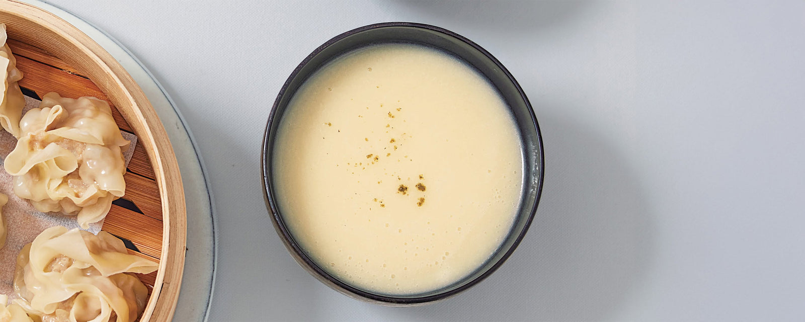 Japanese-style spring sweet onion potage soup in a bowl with black pepper, served alongside shumai dumplings