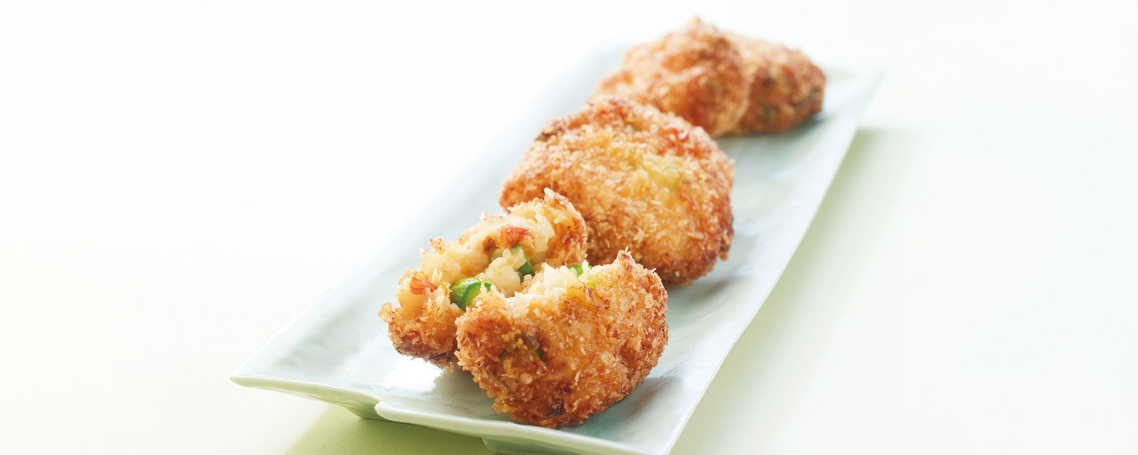 Crispy golden-brown Asparagus and Shrimp Cutlets (Ebi-Katsu) served on a plate, showing a glimpse of green asparagus and plump pink shrimp inside.