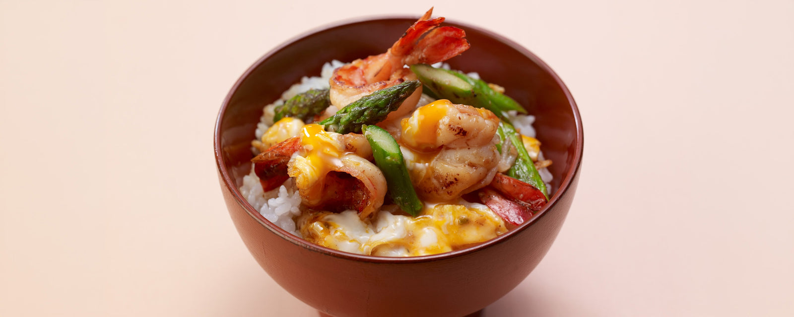 A delicious Japanese rice bowl topped with sautéed shrimp, green asparagus, and fluffy scrambled eggs, seasoned with dashi and butter.