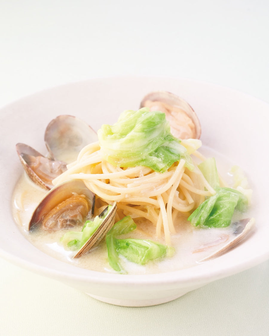 Spring creamy pasta with clams and cabbage in a soy milk sauce, served in a ceramic bowl.