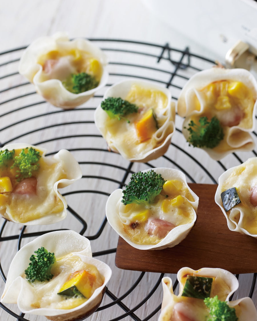 Bite-sized vegetable quiches in crispy gyoza skin shells on a wire cooling rack.